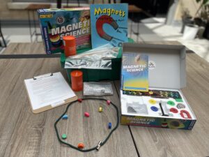 Magnetic experiment kit items, book and game, displayed on table