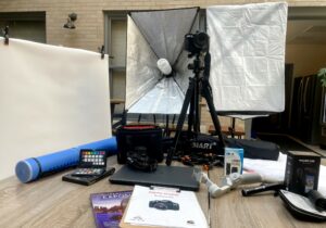 PHoto studio kit contents laid out on table, including camera, tripod, lights, backdrop and various accessories