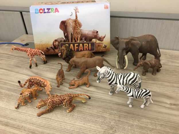 Various plastic safari animal toys on desk